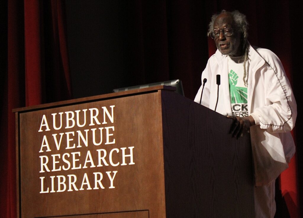 Eusi Kwayana at a podium that says "Auburn Avenue Research Library"